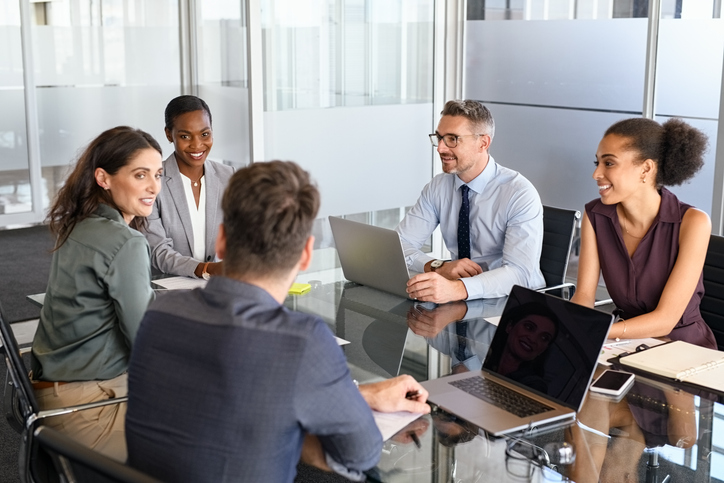 Group of business people have a discussion in conference room. Formal business team brainstorming over new project. Mature businessman and businesswoman talking and working  while sitting in modern conference room with business partners.