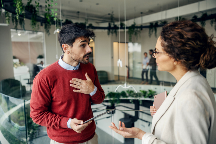 Male and female business colleagues standing in an office, having a serious discussion or argument with intense expressions
